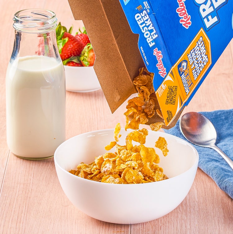 A kitchen counter with a box of Kellogg's Frosted Flakes on it.